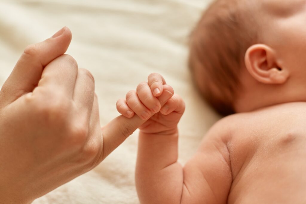 madre-rostro-bebe-desnudo-bebe-sosteniendo-dedo-mama-mama-pasando-tiempo-su-pequeno-hijo-sobre-fondo-claro